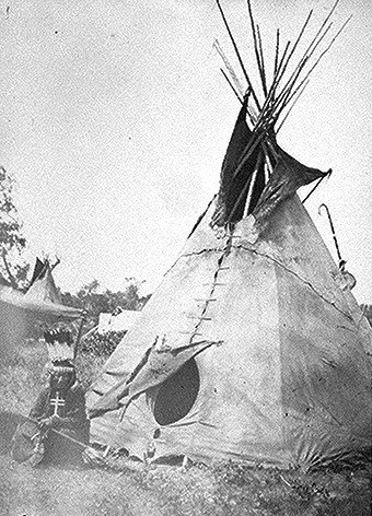 Little Big Mouth, a medicine man, seated in front of his lodge near Fort Sill, Oklahoma, with medicine bag visible from behinid the tent.